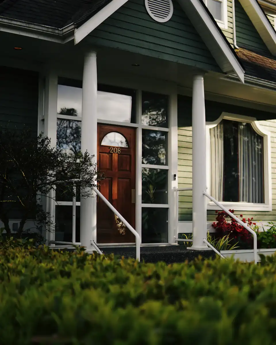 Front porch and entry of a green-sided house with white columns