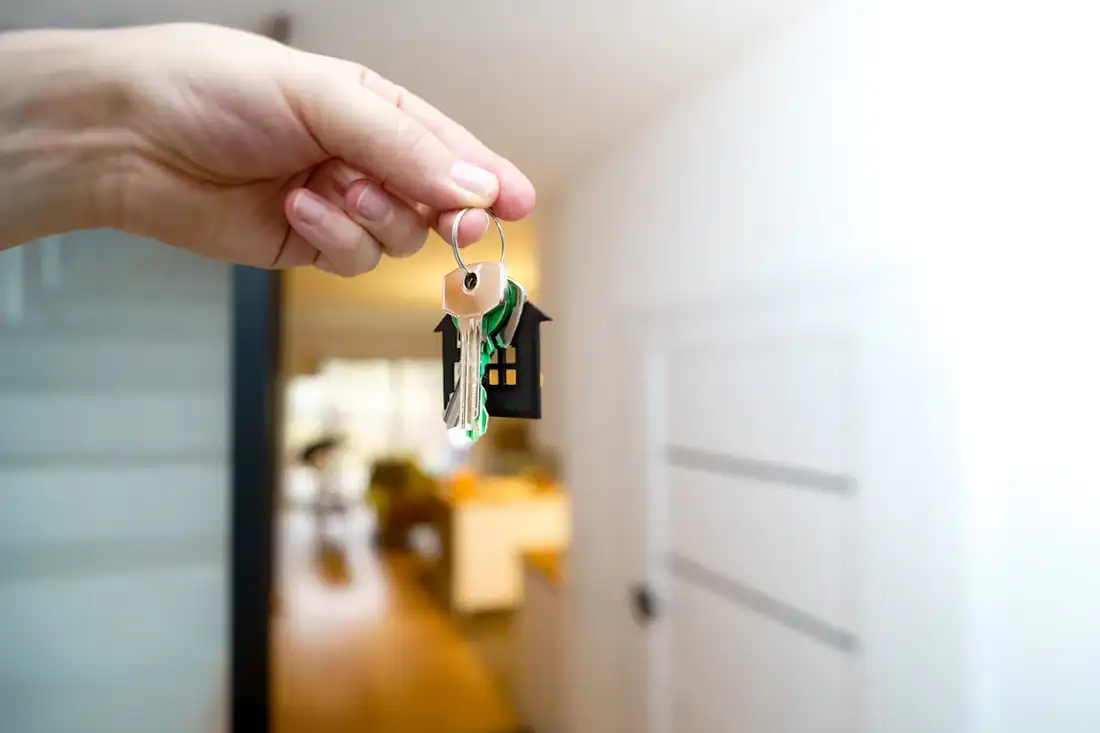 A hand holding house keys inside a front hallway